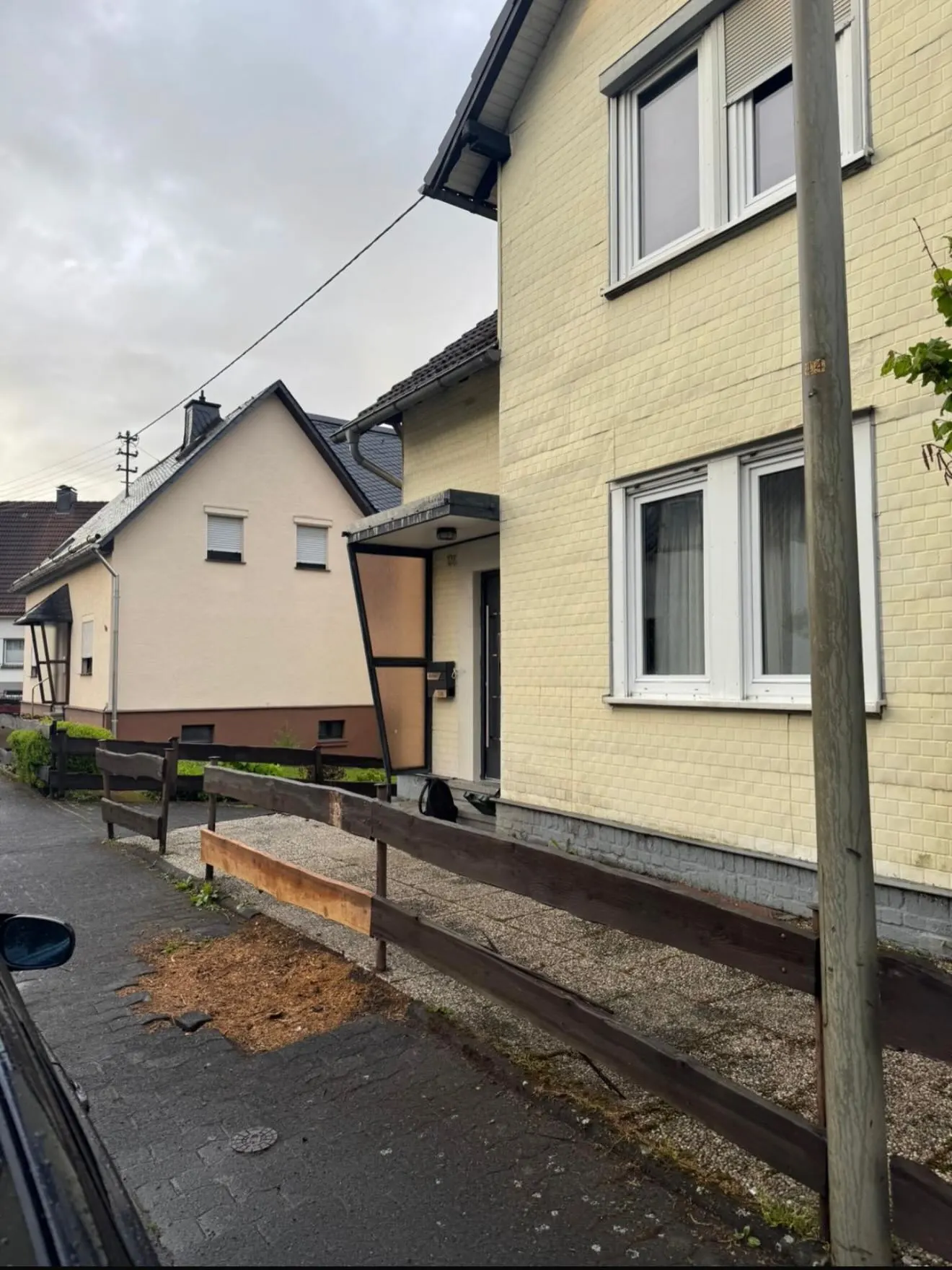 Älterer Holzzaun und Einfassung vor einem hellen Wohnhaus