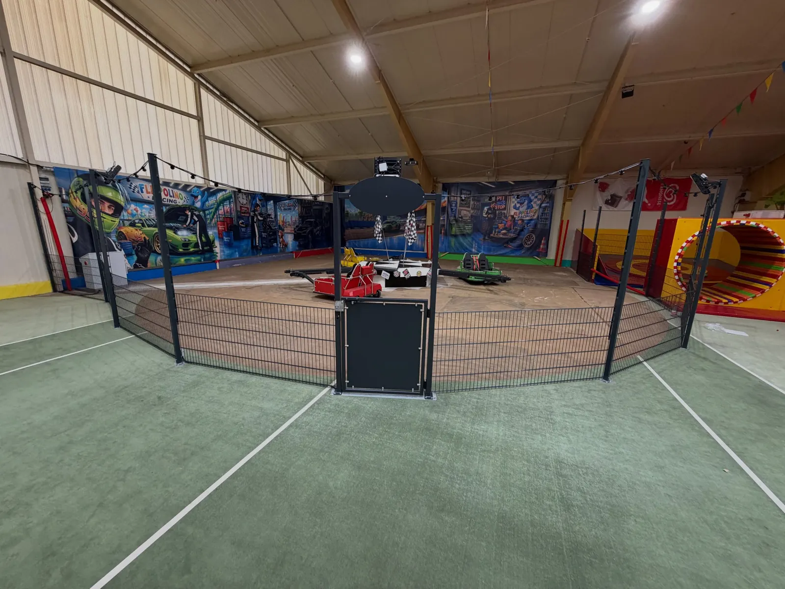 Dunkler Doppelstabmattenzaun mit Tor um eine Spielfläche in einer Halle